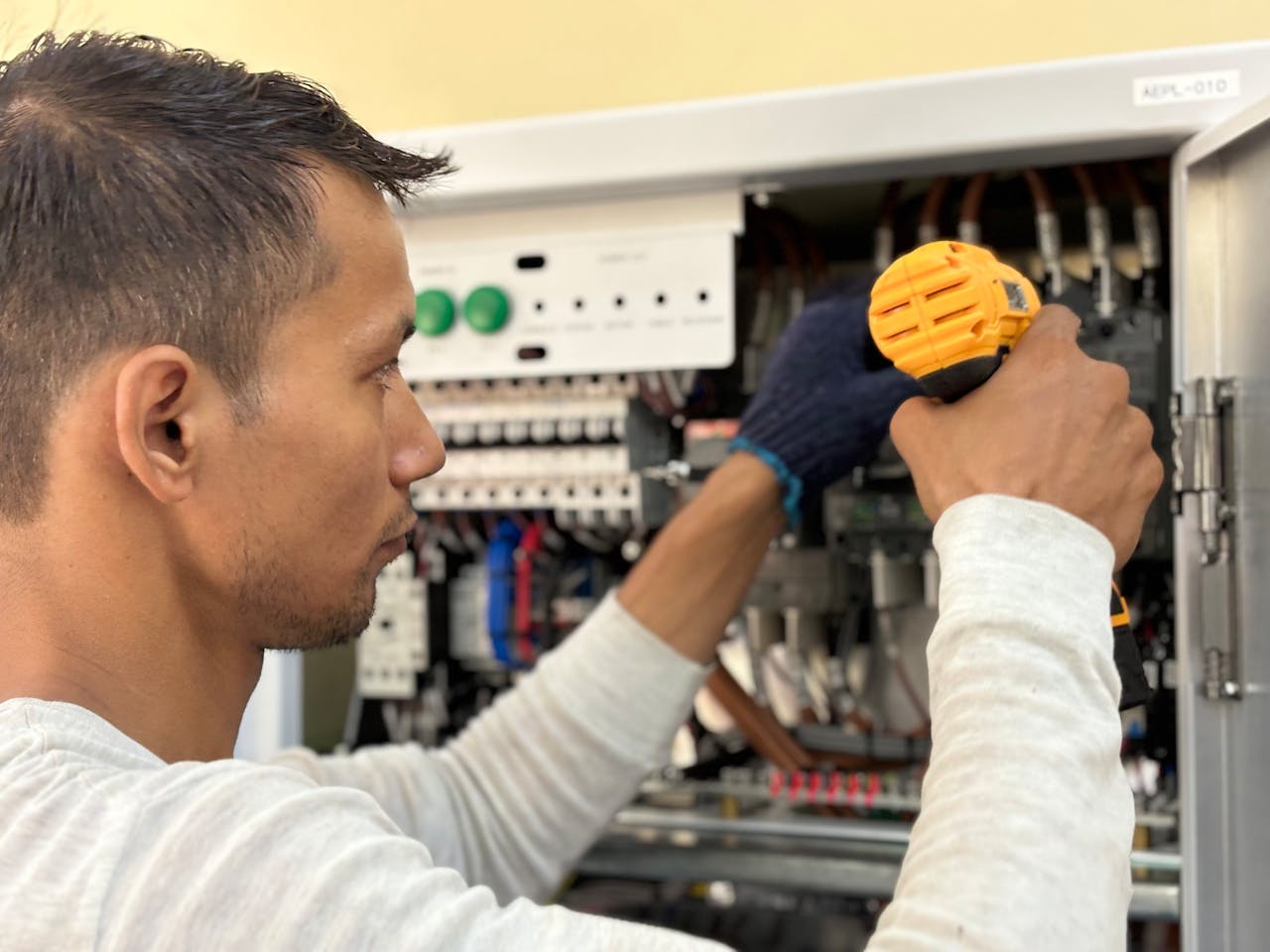 Focused technician using a drill on an electrical panel, showcasing expert workmanship.