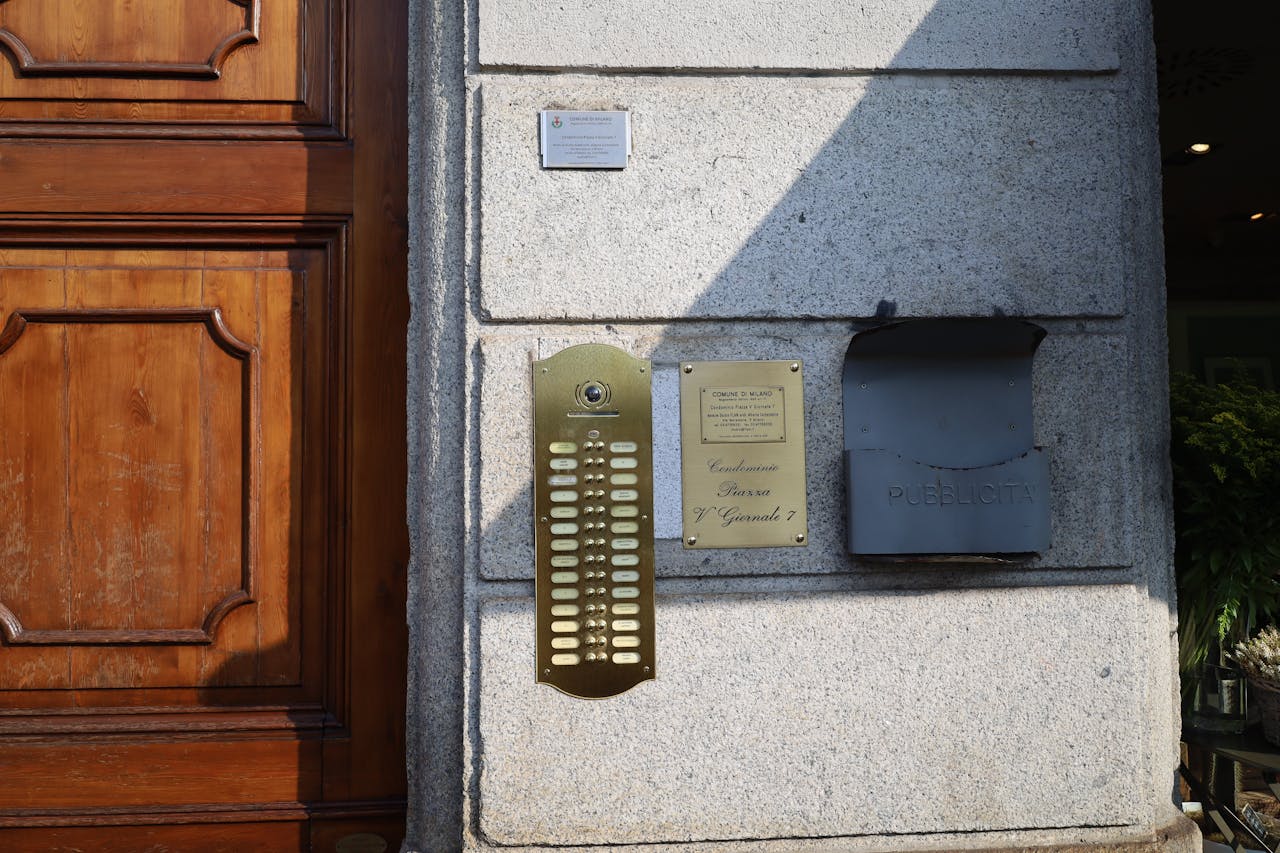 Closeup of a wooden door and metal mailbox with mailboxes in a city setting.